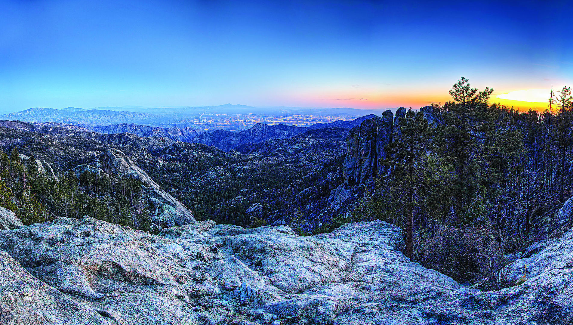 The granite gray summit of Mount Lemmon topped with vibrant colorful streaks across a cold morning sky.