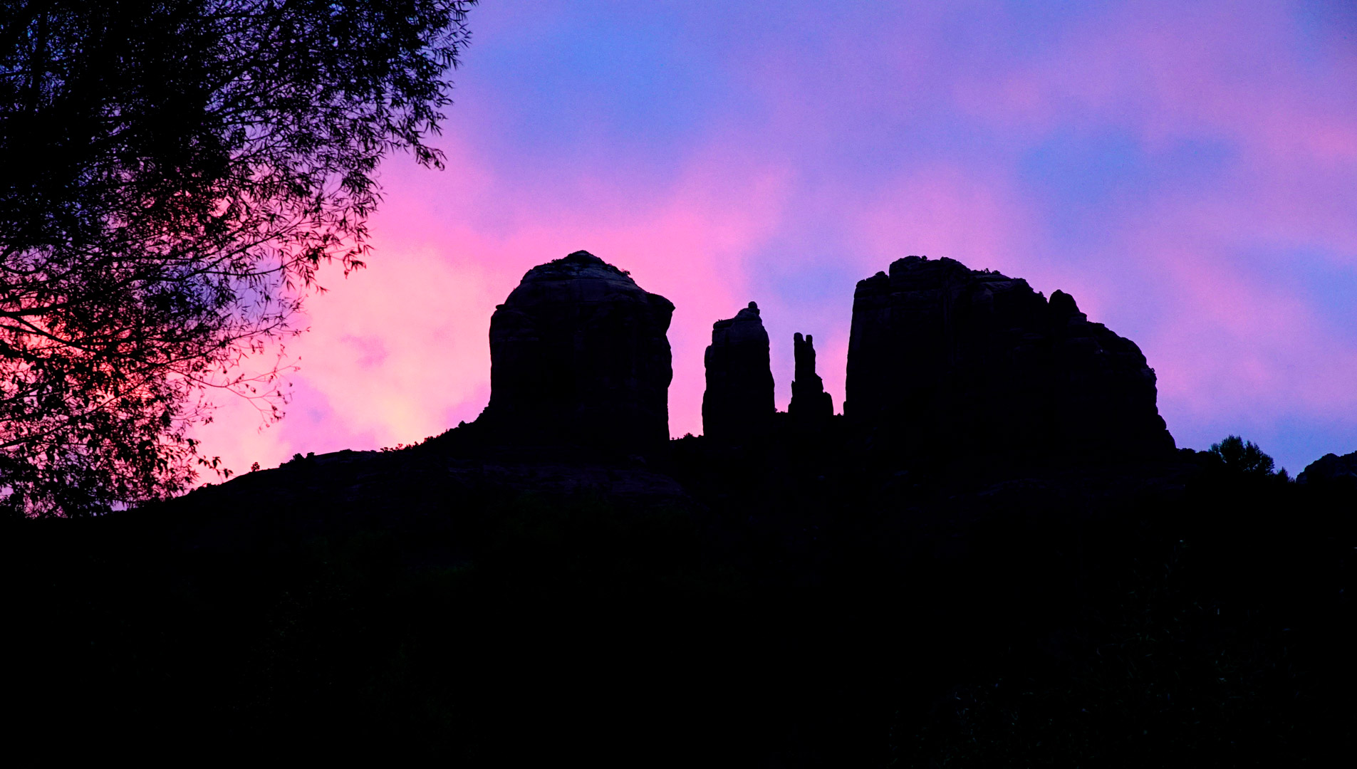 A pink and blue sunset sky behind a black silhouette of Cathedral Rock