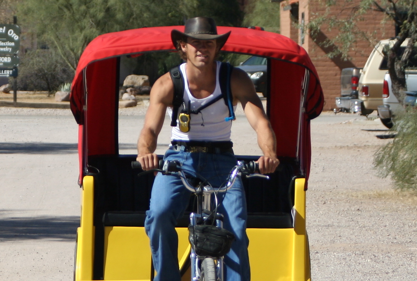 A handsome young man drives a pedicab; a pedal-powered rickshaw.